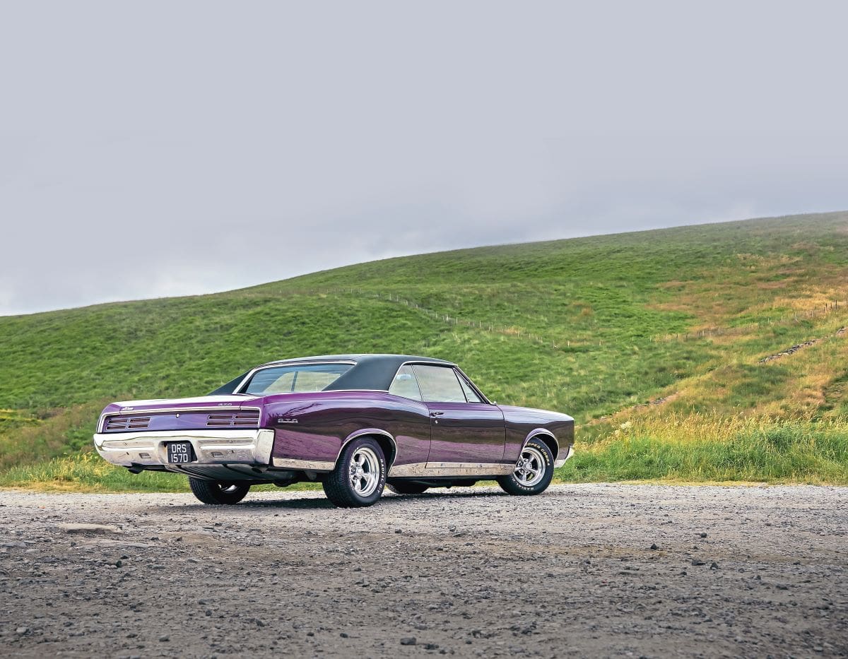Purple 1967 Pontiac GTO from the back, with hills in the background.