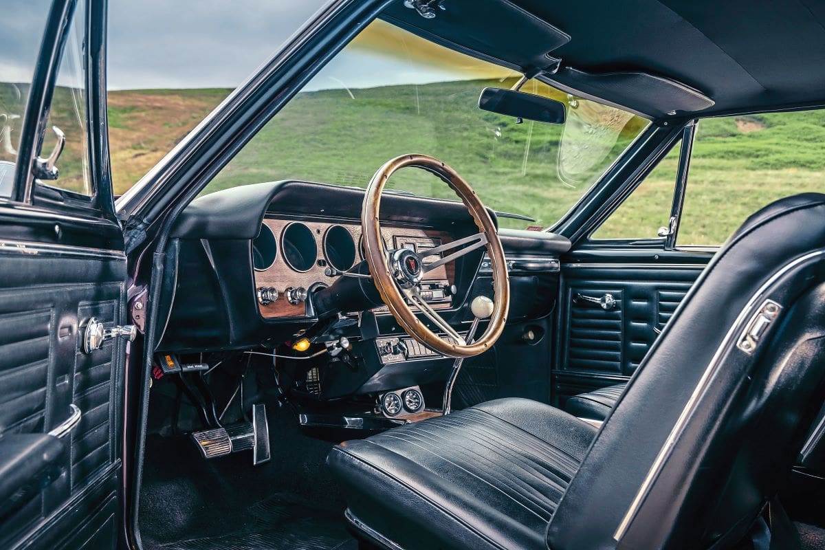 View through the open door of Ian's 1967 Pontiac GTO, showing the leather seats, wood rim steering wheel, and dash