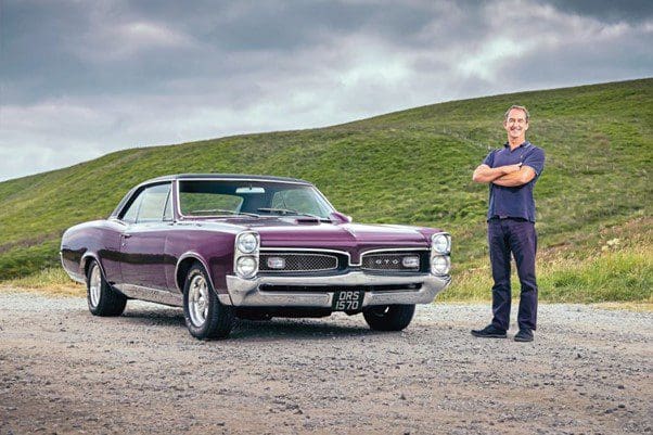 Purple 1967 Pontiac GTO with owner standing next to it