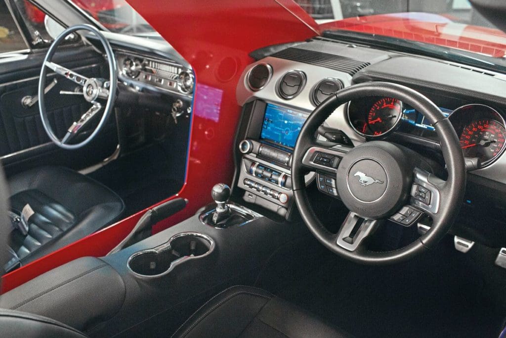 Two steering wheels next to each other from the 1965 and 2015 Mustang.