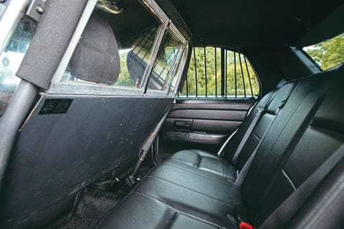 Black leather seats and partition of American police car Crown Vic.