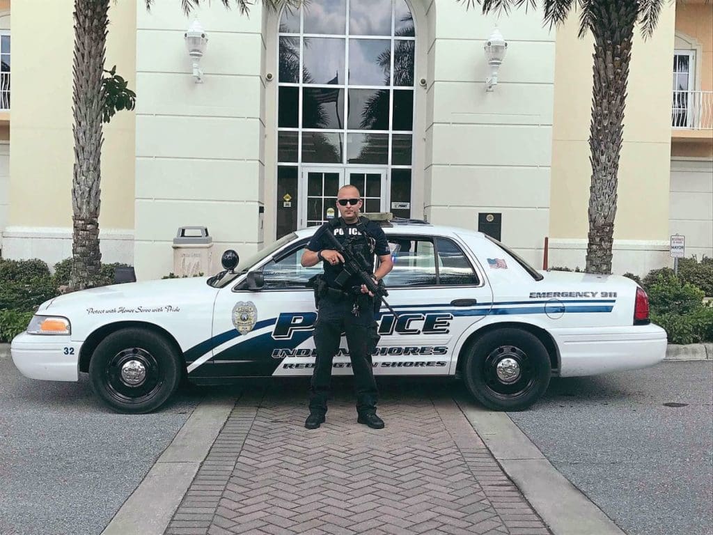 American police officer stands in front of 2011 Ford Crown Victoria P7B Interceptor