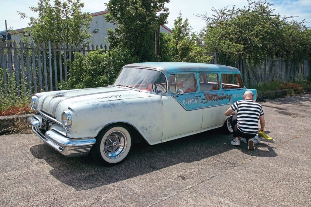 Owner CJ kneeling in front of his 1956 Pontiac Wagon
