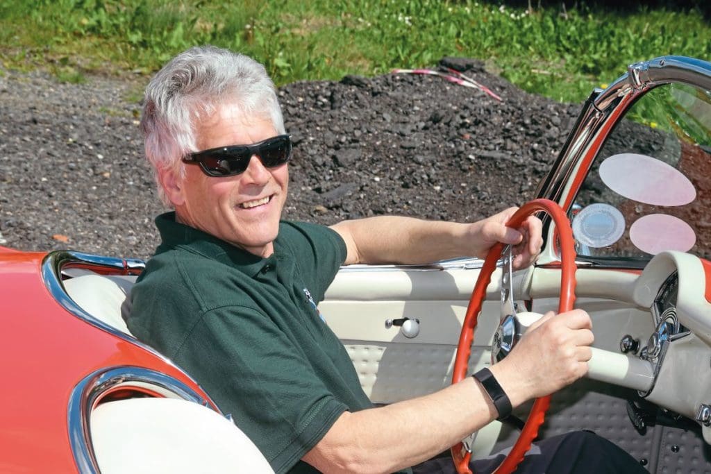 Owner Bob West sits at the wheel of his 1957 Corvette Roadster, smiling at the camera